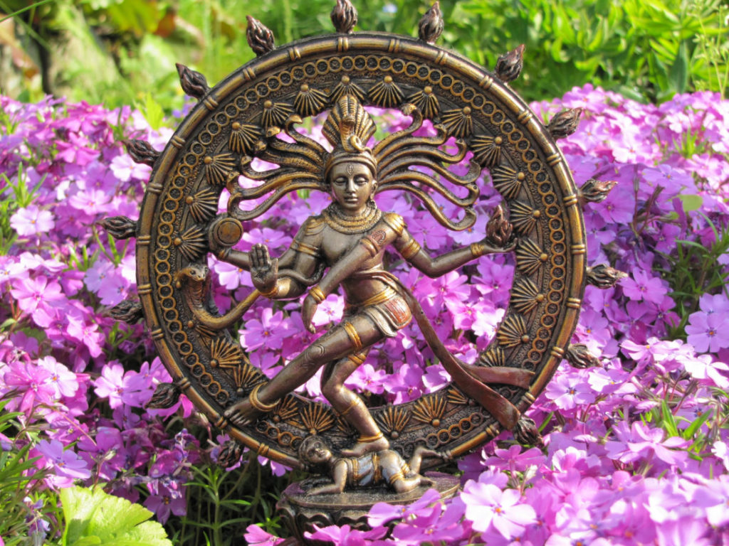 Shiva Nataraja Statue vor lila Blüten im Garten - Über Mich