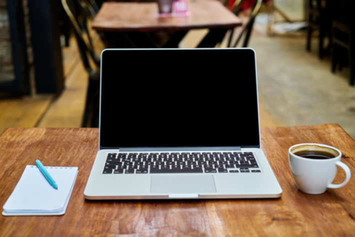 Laptop und Kaffee auf Holztisch - IT-Unterstützung